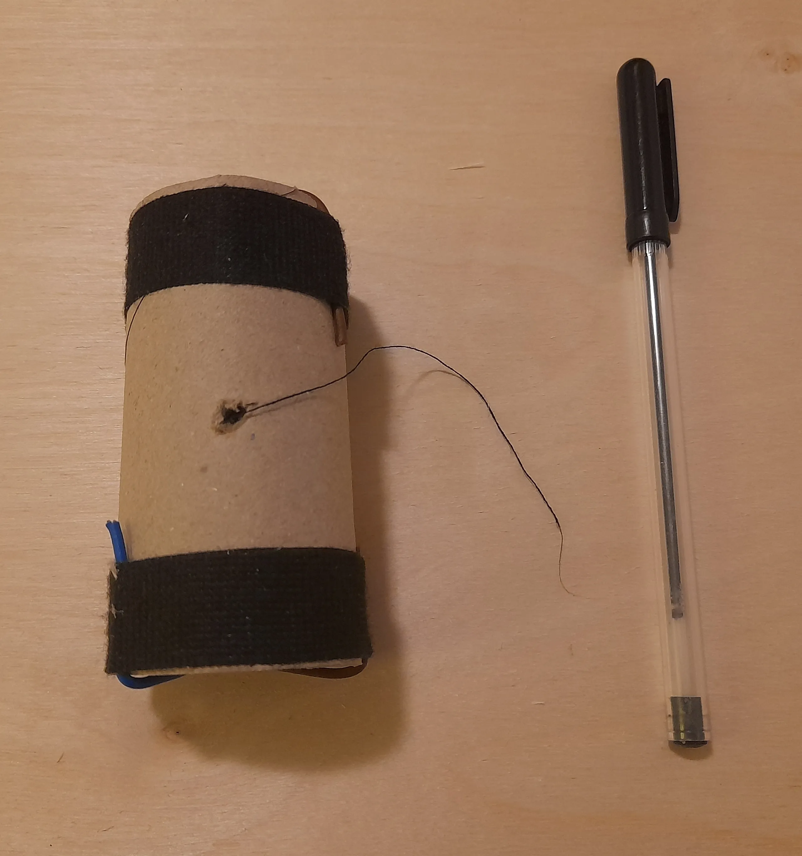 Thread pulled through the small hole, pen alongside the roll